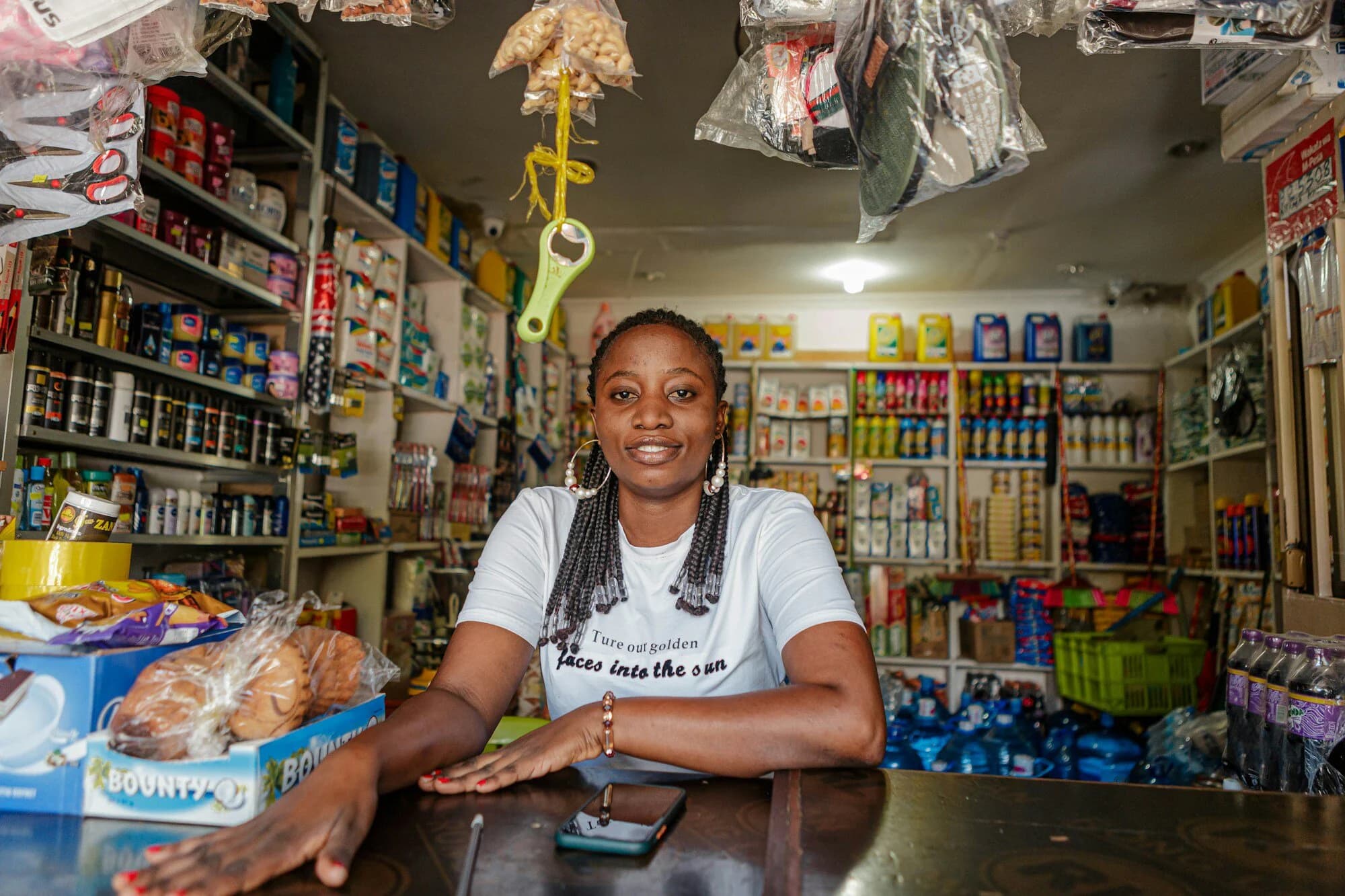 A shopkeeper smiling behind the counter of her well-stocked shop